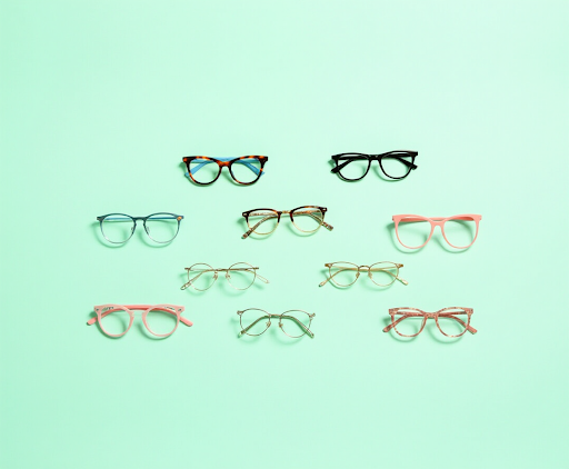 A collection of nine different trendy eyeglass frames, including tortoise shell, pink, and gold round styles, displayed on a mint green background.